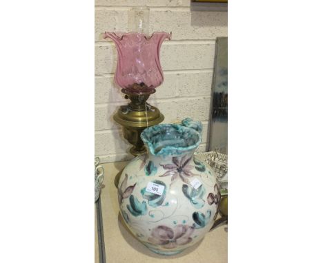 A late-19th/early-20th century oil lamp, the brass reservoir on turned column and circular base, with glass chimney and later