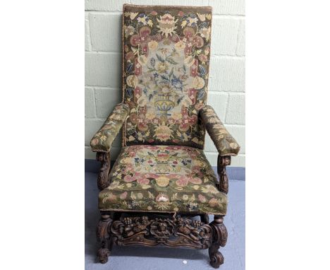 An 18th/19th century walnut framed armchair, with tapestry floral upholstery, the heavily carved frame having scroll arms, bo