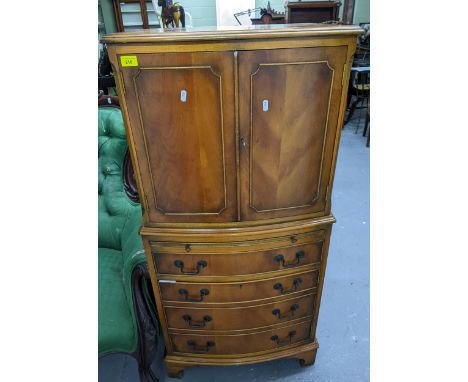 A contemporary yew wood bow fronted cocktail cabinet, twin cupboard doors with internal shelf above a slide, a single drawer 