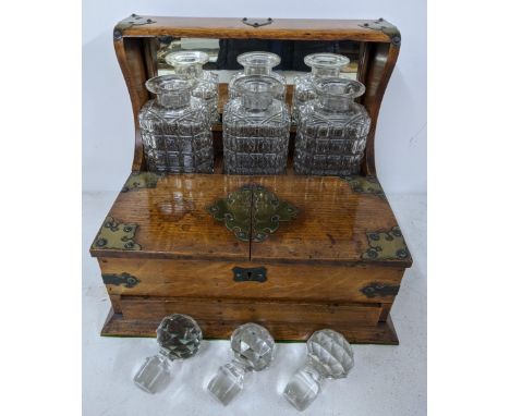 An early 20th century oak Tantalus with twin handles, brass strapware and complete with three decanters Location:If there is 