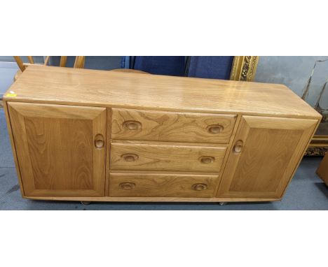 A mid 20th century Ercol blonde elm Windsor sideboard having three central drawers flanked by two cupboard doors, 68.5cm h x 