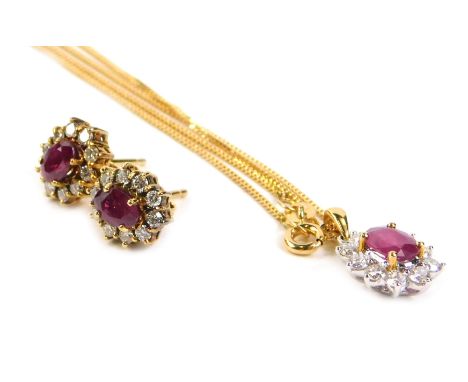 An 18ct gold ruby and diamond pendant and earring set, formed in a floral cluster, with central ruby, surrounded by ten diamo