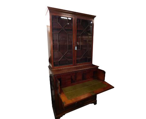A George III mahogany secretaire bookcase, the outswept pediment with dentil moulding,  over a pair of glazed doors, enclosin