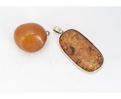 A large amber boulder, mounted with 9ct gold bale, 4cm, together with an amber oval pendant with yellow metal mount, 7cm x 3.