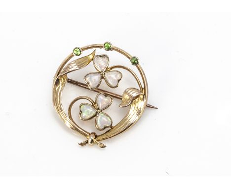 An Edwardian Art Nouveau 15ct opal and demantoid garnet circular brooch, the two clover leaves set with heart cut opals withi