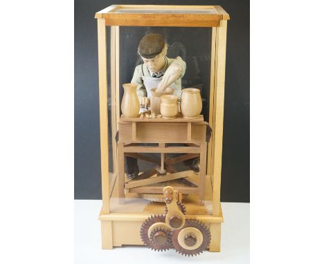 Cased Mechanical Wooden Automaton of a Potter at his Wheel, the cased inscribed with a monogram, Potter and 28/250, 53cm high