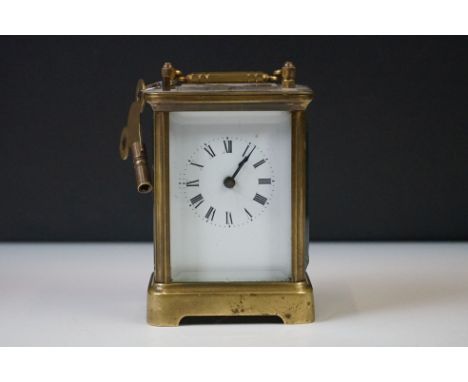 A brass cased carriage clock with beveled glass panels and white enamel dial, complete with key. 