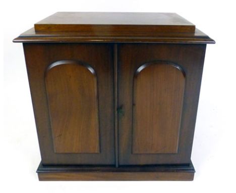 An early Victorian mahogany two door table cabinet, the arched panel doors opening to reveal a bank of nine drawers with flus