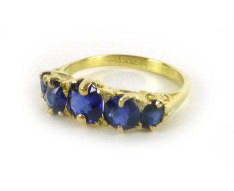 An 18ct yellow gold ring set five graduated blue coloured stones in a scrollwork setting, ring size N, 3.7 gms CONDITION REPO