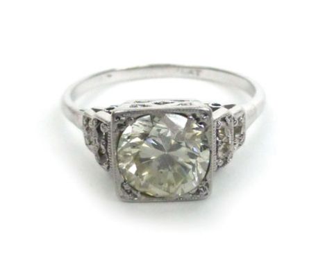  A platinum ring set single diamond in a square raised open work setting, the shoulders each set three further diamonds, cent