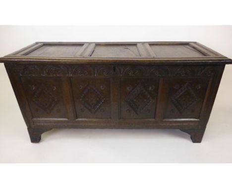 A late 17th century oak coffer with a three panel top lifting to reveal a vacant interior over a carved four panel front, h. 
