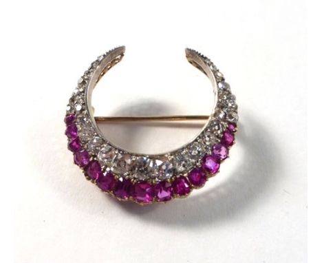 A yellow gold and platinum highlighted brooch in a crescent moon set diamonds and rubies, estimated total diamond weight appr