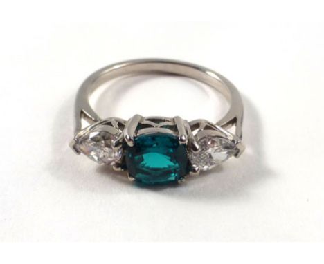 A white gold ring set cushion cut vibrant emerald and two teardrop cut diamonds within a raised openwork setting, estimated e