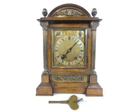 A late Victorian oak and brass mounted bracket clock with arched pediment flanked by brass acorn finial's over Corinthian col