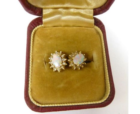 A pair of 14ct yellow gold stud earrings, each set an oval opal in a surround of twelve small diamonds, overall, 2 gms