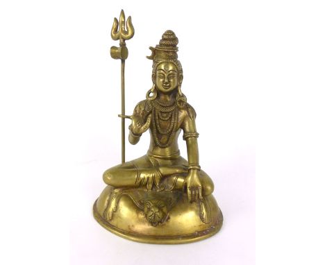 A cast brass figure of a seated Indian deity sitting cross legged upon tiger pelt with fixed trident and an out-stretched pal