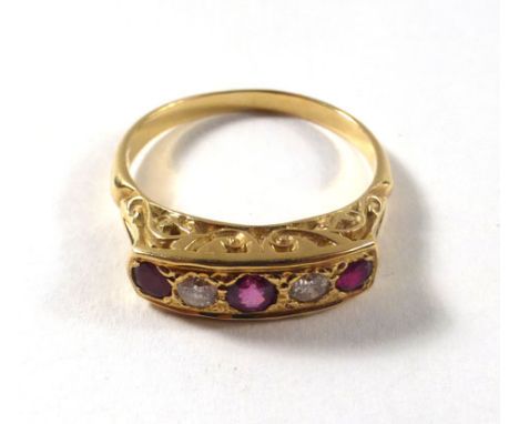 An 18ct yellow gold ring set three graduated rubies interspersed with two small diamonds within a recessed scrollwork setting