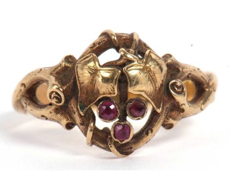Mid grade yellow metal and ruby ring, an open work ivy leaf and branch design highlighted with three small rubies, the twiste