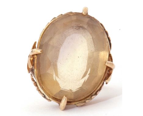 Large lemon citrine dress ring, the oval faceted citrine in cardinal set and raised between chased and textured leaf decorate