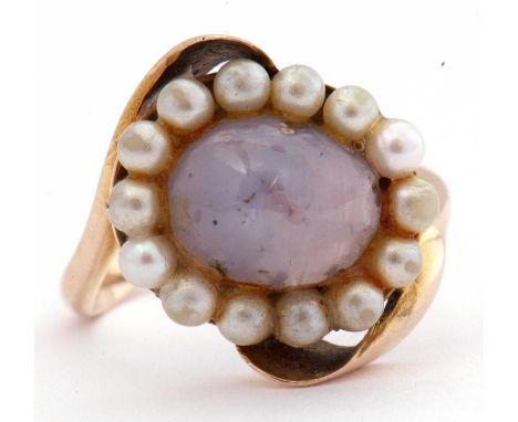 9ct gold star sapphire and seed pearl ring, the cabochon sapphire set within a surround of small seed pearls between angular 