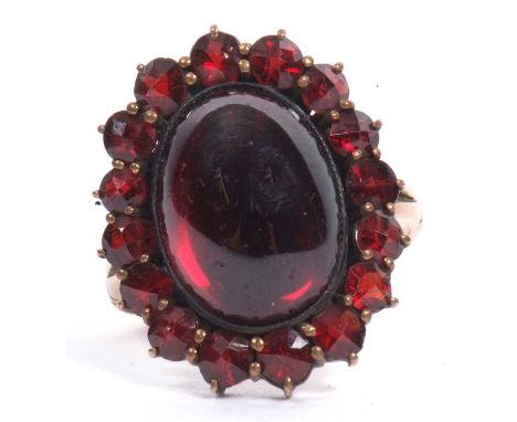 Bohemian style garnet cluster ring, the central cabochon surrounded by faceted smaller stones, size J-K