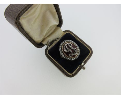 the initials delineated in rose cut diamonds on an oval dark red enamel ground to a rose cut diamond border, closed back, tri