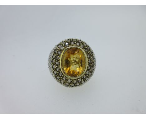with an oval cut golden yellow citrine collet set in a bombé border pavé set with two rows of round cut smoky quartzes and th