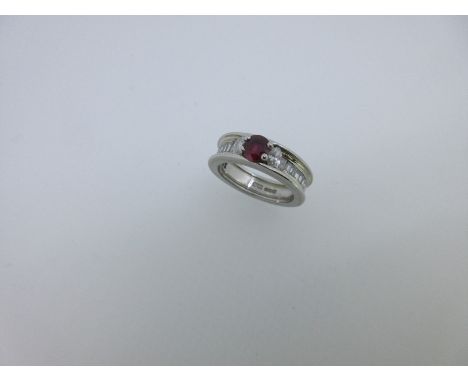 with a round cut ruby between two marquise cut diamonds, above a channel set line of trapezoid baguette diamonds, all within 