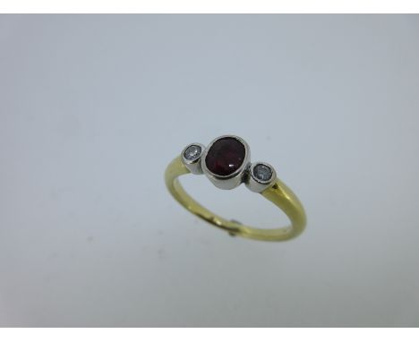 the oval cut ruby between two round brilliant cut diamonds, all collet set in white gold to a plain yellow gold shank, size L