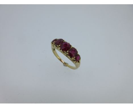 the graduated oval cut rubies, of fine transparent crimson lake colour, claw set to a carved scrolling mount, reeded shoulder