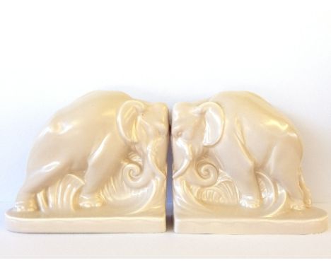 A pair of Poole Pottery buff glazed bookends, modelled as Elephants, shape 814, after a design by Harold Brownsword.