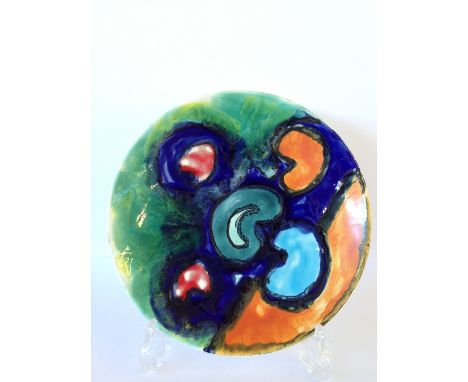 A Poole Pottery Studio dish, decorated in an abstract pattern in vivid tones of orange, blue, green and red.