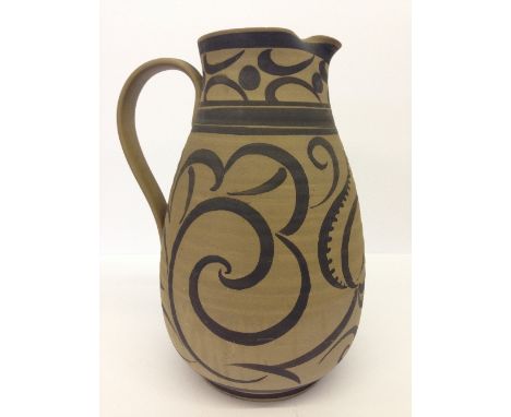 A large unglazed Poole Pottery jug hand painted with brown slip on brown high fired biscuit from an original design of James 