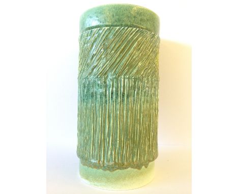 A Poole Pottery early Delphis cylindrical carved vase, decorated in tones of green (9 inches).