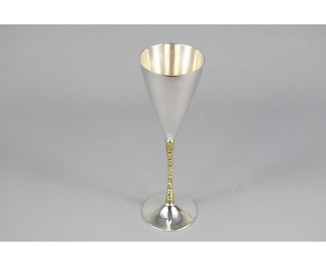 Stuart Devlin champagne flute; the silver gilt flaring conical flute with Falcon award, approx 22.5 cms h, in the original pr