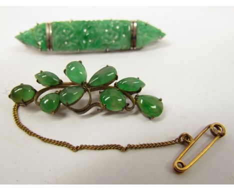 A carved Jade panel brooch stamped 9ct 5528, 6cm long and a cabochon frond form brooch, unmarked