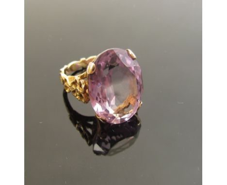 A gold ring set with large oval amethyst 20mm x 15mm in four claw mount, decorative floral shoulders stamped 9ct. Size O, 8g