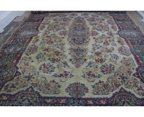 A Kirman carpet, the ivory field with floral central medallion and border, 430 x 306cm.