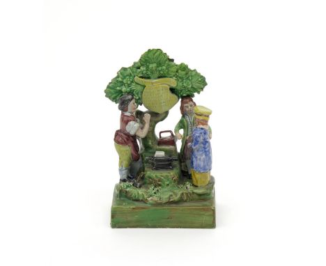 A Staffordshire Gretna Green figure group, c.1820, of a couple standing before a blacksmith beneath a tree in which is suspen