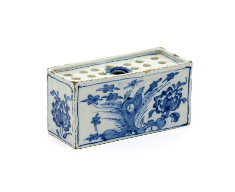 A small delftware flower brick, c.1760, of rectangular form, the long sides painted with peony sprays beside holey rockwork, 