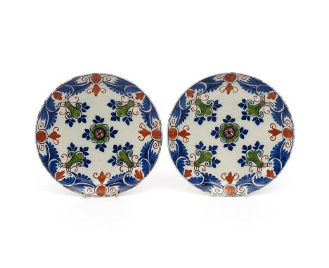 A pair of London delftware plates, c.1720, painted in blue, red and green with a formal design of fleur de lys motifs around 