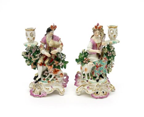 A pair of Derby candlestick figures of musicians, c.1765, seated beside sconces above flowering bocage, she playing the lute 