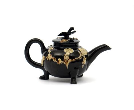 A small Astbury-type teapot and cover, mid 18th century, the flattened globular body raised on three paw feet, applied with f