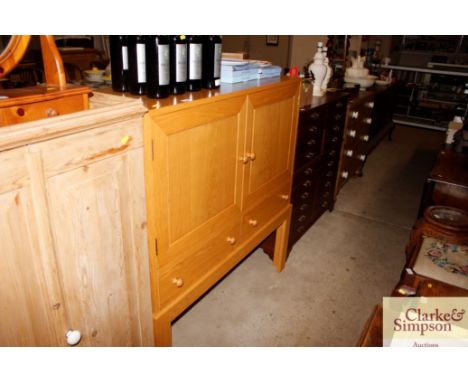 A light oak side cabinet enclosed by a pair of doors, two drawers below 