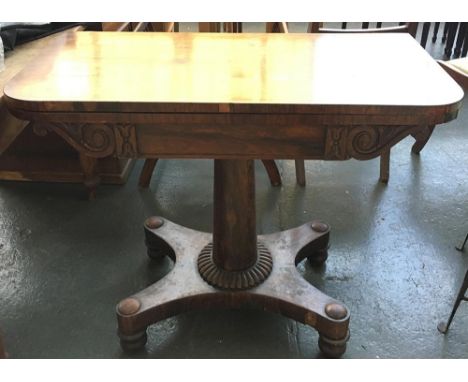 An early 19th century rosewood swivel top card table, on tapering column and quatreform base with bun feet 