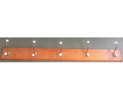 A five hook coat rack, the brass hooks with ceramic terminals, 137cmL 