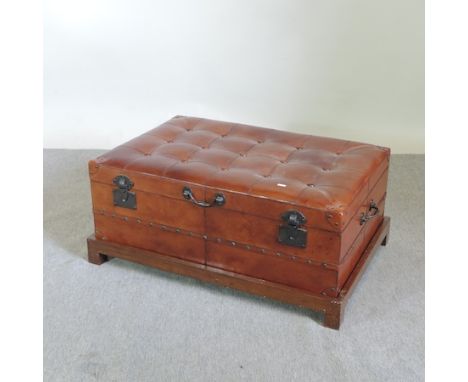 A brown leather upholstered trunk, on a wooden plinth, 97cm