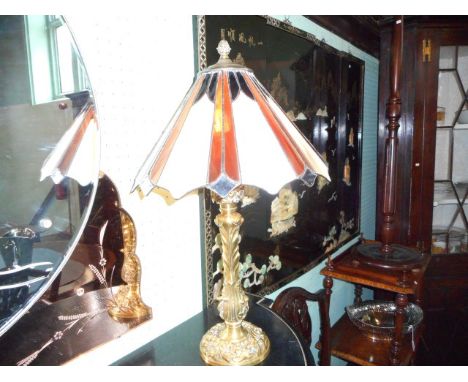 A cast gilt metal table lamp, the florally decorated column beneath Tiffany-type shade.