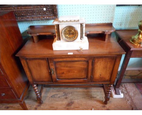 A 1920's oak washstand, having a shaped shelf over trinket drawer, the base with panelled cupboard door on bobbin turned and 