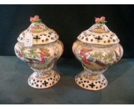 A pair of 20th century Continental porcelain pot pourri and covers, each having fruit finial and decorated in the Chelsea man